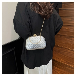 Detail of silver woven clutch bag featuring golden metal handle and chain shoulder strap