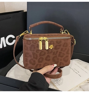 Close-up of leopard print bag with golden flower hardware and double zipper detail