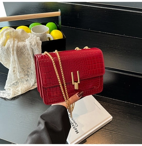Detailed view of red crocodile-patterned bag with golden U-shaped lock and chain strap