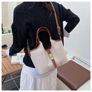 Detail of canvas tote bag with brown leather trim and golden twist lock closure