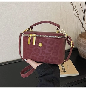 Detail of burgundy leopard print mini box bag with top handle and gold flower hardware