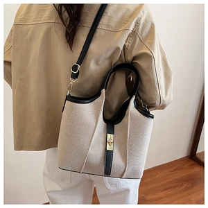 Detail of canvas tote bag showing high-quality leather trim and gold metal swivel lock
