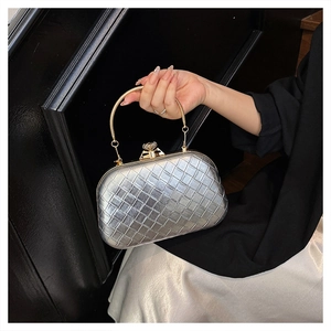 Macro shot of silver woven texture clutch with gold circular handle and rhinestone detail