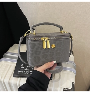 Macro shot of grey leopard embossed leather bag with gold floral zip detailing