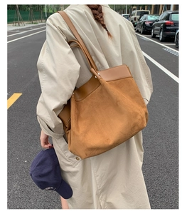 Outdoor shot of a large brown suede patchwork tote bag paired with a beige trench coat