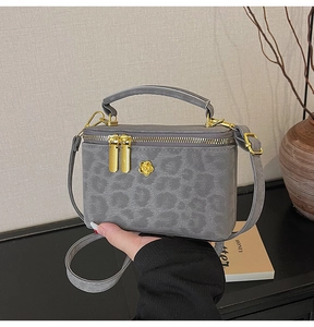 Detail of grey leopard embossed mini box bag with golden floral clasp and top handle