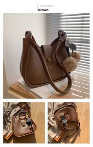 Detail van een bruine Hobo-crossbodytas van zacht PU-leer met een schattige berenhanger