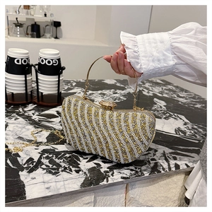 Dettaglio pochette da sera con onde di perline dorate, manico in metallo e gemma