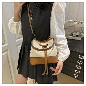 Lifestyle shot of a cream canvas and brown leather bucket bag with drawstring closure