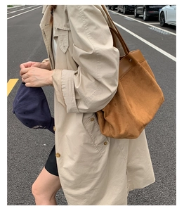 Detailed view of brown retro canvas tote bag with smooth leather trim on female model
