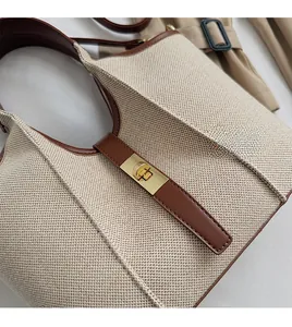 Detail of canvas bucket bag with brown leather trim and golden twist lock closure