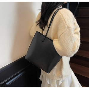 Minimalist black tote bag shown from side view on a model for a chic urban fashion look