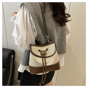 Detail of canvas bucket bag with leather drawstring on shoulder for minimalist style
