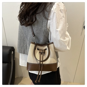 Detail view of canvas bucket bag with brown leather trim and drawstring closure