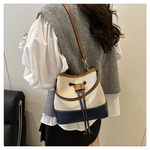 Detail view of canvas bucket bag featuring blue leather trim and drawstring closure