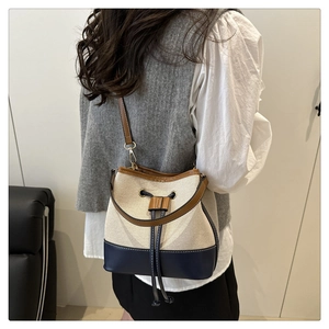 Three-color bucket bag with canvas stitching and drawstring closure worn by model