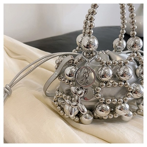 Detail view of silver beaded bag with futuristic hollow weave and dog charm