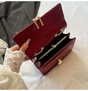 Detail shot of a dark red crocodile pattern bag with gold chain strap and inner zipper compartment
