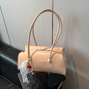 Sac à main rose pastel en PU avec breloque cerise et bandoulière devant un mur texturé