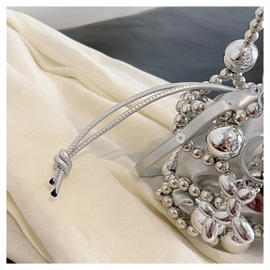 Detail of silver drawstring handbag with metallic beads and balloon dog charm