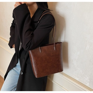 Close-up of vintage dark brown faux leather tote bag with elegant thin shoulder straps