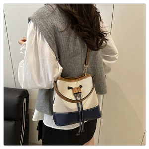 Detail view of canvas bucket bag with leather patchwork and drawstring closure on model