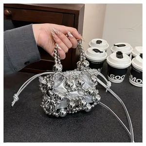 Detail of silver metallic sphere handbag with drawstring closure and slim shoulder strap