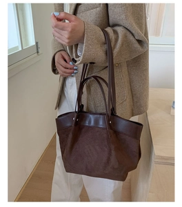 Detailed side view of dark brown tote bag with suede and smooth leather stitching