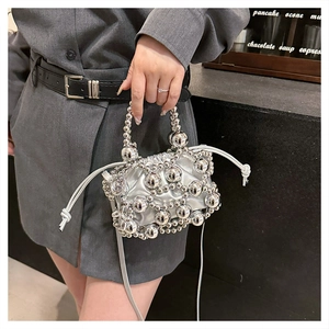 Detail of silver beaded crossbody bag with drawstring closure and metal ball texture