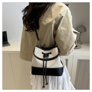 Detail of canvas bucket bag with black leather patchwork and drawstring closure