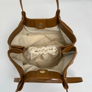 Detail view of large brown tote bag with canvas lining and magnetic buckle closure