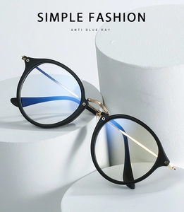 Detail view of round black anti-blue light glasses with gold metal bridge and temples