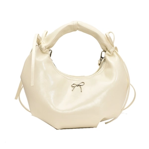 Sac hobo blanc crème avec nœud argenté et base plissée sur un fond blanc impeccable