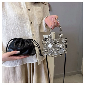 Detailed close-up of a black drawstring cloud bag and a silver beaded bag with a bear charm