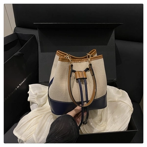 Detailed view of canvas bucket bag with tri-color leather trim and drawstring closure