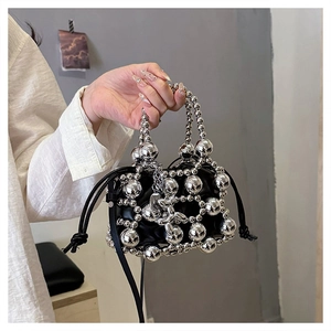 Close-up of silver metal bead cage bag with a black drawstring pouch and handle detail