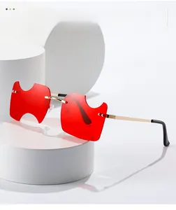Détail de lunettes de soleil rouges sans monture avec verres dentelés et branches dorées