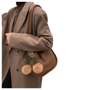 Vintage brown leather crossbody bag with cherry pom-pom charm in a semi-circle shape
