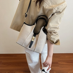 Canvas tote bag with leather trim and gold twist-lock shown from a 45-degree angle