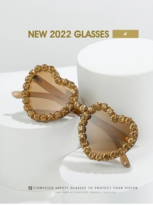 Détail macro de lunettes de soleil en forme de cœur avec strass dorés et verres bruns