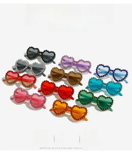 Lunettes de soleil cœur serties de strass colorés présentées en plusieurs coloris