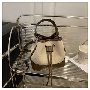Minimalist canvas bucket bag with leather trim on a stylish display cart