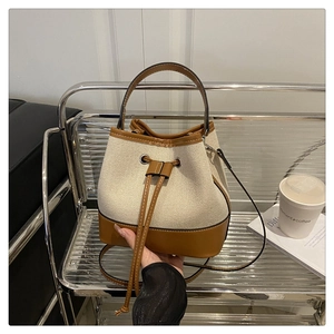 Minimalist canvas bucket bag with brown leather trim and drawstring closure handheld style