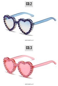 Détail de lunettes de soleil en forme de cœur avec strass brillants en bleu et rose