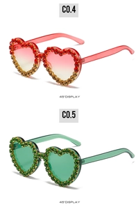 Vue détaillée de lunettes de soleil en forme de cœur avec strass brillants en rouge et vert