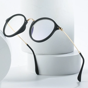 Classic round glasses with matte black frames and gold metal temples on a minimalist stand