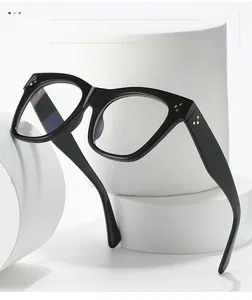 Detail of square black glasses frame with three golden rivets on thick acetate