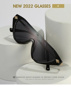 Detailed macro view of black cat-eye sunglasses with iconic gold arrow metal hinge accents