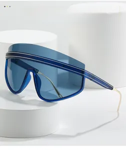 Close-up of deep blue one-piece sunglasses with sleek gold metal temples on a white stand