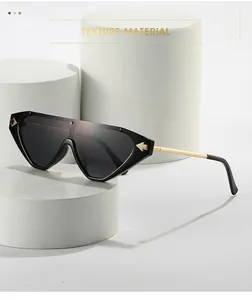 Detail of black geometric sunglasses with golden arrow hardware and sleek metal temples